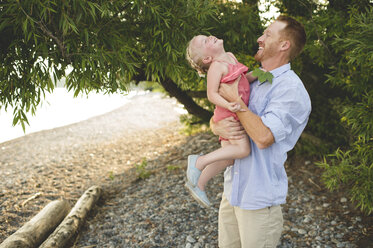 Mid adult man carrying and tickling daughter at Lake Ontario, Oshawa, Canada - CUF20911