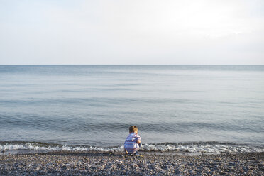 Rückansicht eines kleinen Jungen, der am Ontariosee hockt und spielt, Oshawa, Kanada - CUF20912