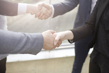 Mid section of businesswomen and businessmen shaking hands - CUF20976