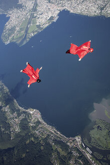 Zwei Wingsuit-Fallschirmspringer trainieren im Team und fliegen eng zusammen über dem See, Locarno, Tessin, Schweiz - CUF21012
