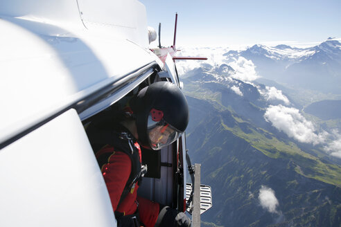 Fallschirmspringerin im Helikopter bei der Ausstiegskontrolle über dem Berg, Interlaken, Bern, Schweiz - CUF21027