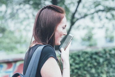 Junge Frau spricht im Park mit ihrem Smartphone - CUF21125