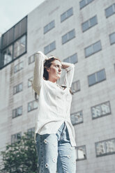 Low angle view of young woman with hands on head outside office building - CUF21127