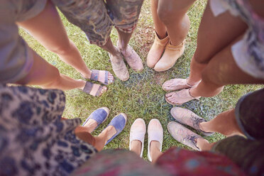 Group of friends at festival, covered in colourful powder paint, standing in circle, elevated view of feet - CUF21185