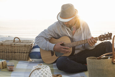 Junger Mann spielt Gitarre am sonnenbeschienenen Strand, Kapstadt, Westkap, Südafrika - CUF21202