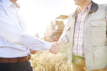 Ausschnitt eines Landwirts und eines Geschäftsmanns in einem Weizenfeld beim Händeschütteln - CUF21219