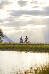 Österreich, Tirol, Mountainbiker im Abendlicht - CVF00645