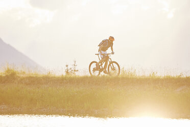 Österreich, Tirol, Mountainbiker im Abendlicht - CVF00648