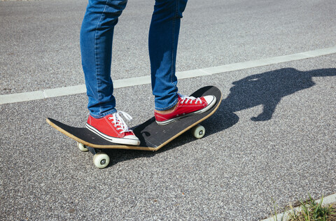 Woman standing on broken skateboard stock photo