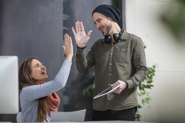 Two colleagues giving a high five at desk in office - ZEF15522