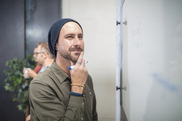 Junger Mann denkt am Whiteboard im Büro - ZEF15529