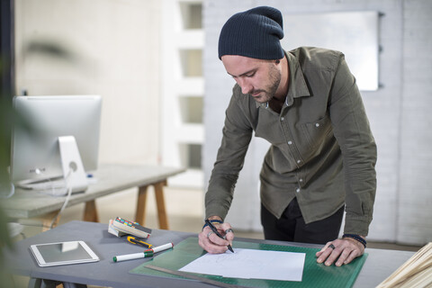 Junger Mann macht sich Notizen am Schreibtisch im Büro, lizenzfreies Stockfoto