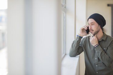 Junger Mann am Handy am Fenster im Büro - ZEF15551