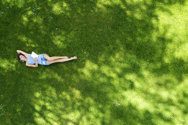 Young woman lying on meadow, using tablet - MAEF12610