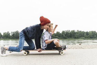 Glückliche Jungs auf dem Skateboard am Flussufer - UUF13936