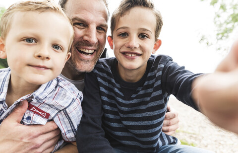 Selfie eines glücklichen Vaters mit zwei Söhnen im Freien, lizenzfreies Stockfoto