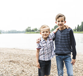 Portrait of two smiling boys embracing at the riverside - UUF13952