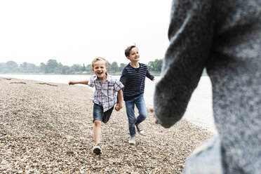 Happy boys running towards father at the riverside - UUF13953