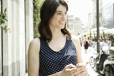 Woman on city street texting on smartphone, Milan, Italy - CUF21236