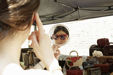 Spiegelbild einer Frau, die eine Sonnenbrille an einem Marktstand anprobiert, Mailand, Italien - CUF21244