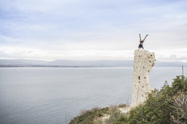 Männlicher Kletterer im Handstand auf einer Turmruine an der Küste, Cagliari, Italien - CUF21251