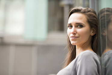 Portrait of young businesswoman leaning against office exterior, London, UK - CUF21311