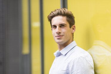 Portrait of young businessman leaning against office exterior, London, UK - CUF21314