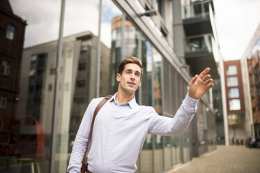 Young businessman hailing a cab outside office, London, UK - CUF21328
