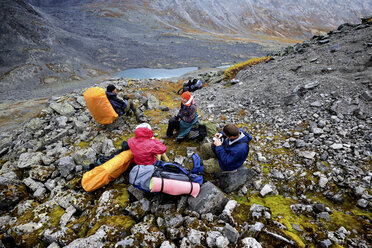 Vier erwachsene Wanderer machen eine Pause in einer zerklüfteten Tallandschaft, Khibiny-Gebirge, Kola-Halbinsel, Russland - CUF21330