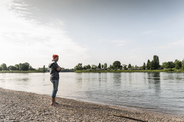 Mature man with red beanie enjoying Rhine riverbank - UUF13966