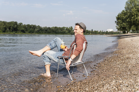 Älterer Mann sitzt auf einem Stuhl am Rheinufer, lizenzfreies Stockfoto