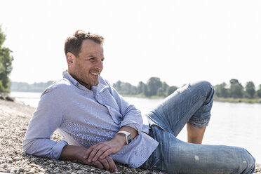 Mature man lying at Rhine riverbank - UUF13982