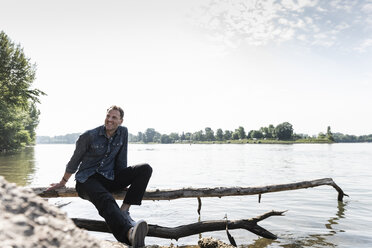 Mature man sitting at Rhine riverbank - UUF13987