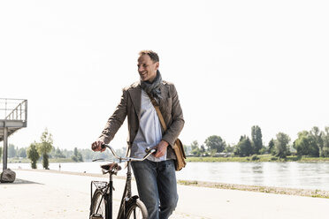 Älterer Mann mit Fahrrad am Rheinufer - UUF13998