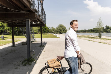 Mature man with bike at Rhine riverbank - UUF14011