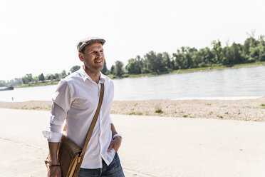 Mature man wearing flat hat at Rhine riverbank - UUF14018