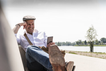 Mature man using smartphone on bench - UUF14020
