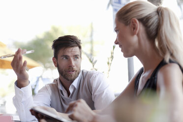 Mature man and woman sitting outside cafe, having discussion - ISF07507