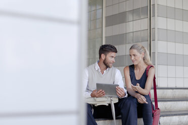 Älterer Mann und Frau sitzen im Freien und schauen auf ein digitales Tablet - ISF07514