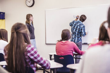 Jugendlicher schreibt Gleichung auf Whiteboard in High School Klasse - ISF07545