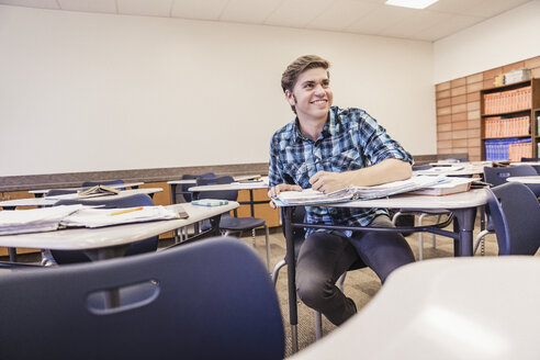 Jugendlicher macht Notizen am Schreibtisch im Klassenzimmer einer High School - ISF07548