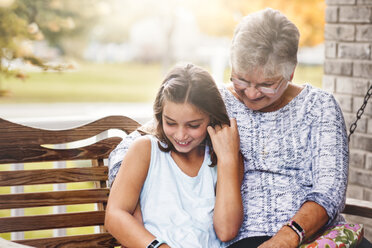 Grandmother and granddaughter sitting on porch swing, laughing - ISF07580