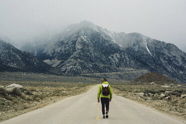 Rear view of hiker on road by mountains, Lone Pine, California, USA - ISF07608