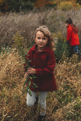 Porträt eines Mädchens und ihrer Schwester beim Pflücken von Wildblumen auf einem Feld - ISF07634