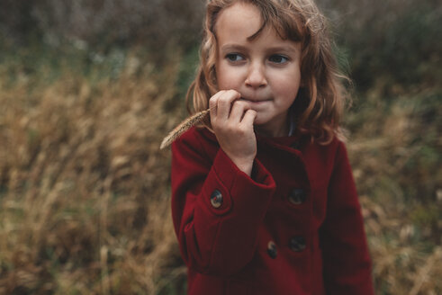 Porträt eines Mädchens, das langes Gras auf einem Feld kaut - ISF07637