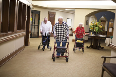 Three senior adults walking indoors with walking frames - ISF07690