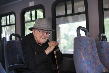 Portrait of senior man sitting on train, holding walking stick - ISF07693