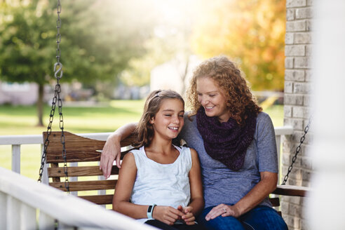Tante und Nichte sitzen lächelnd auf einer Veranda-Schaukel - ISF07709