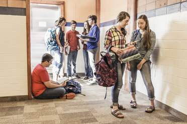 Gymnasiasten beim Lesen von Heften im Schulkorridor - ISF07844