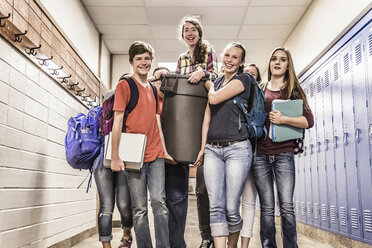 Porträt von Gymnasiasten, die ein junges Mädchen in einem Behälter in der Umkleidekabine tragen - ISF07849